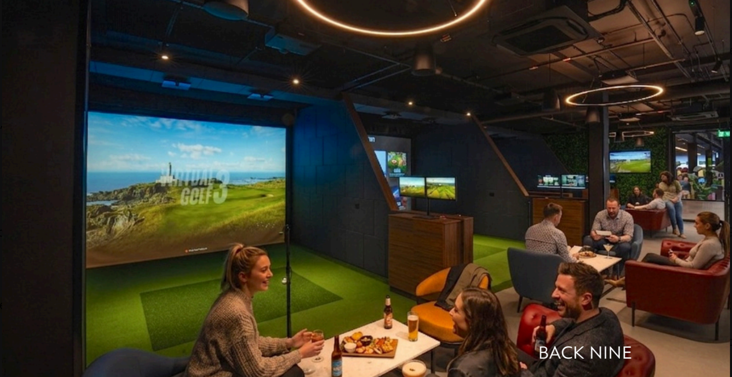 The Back Nine at Five Iron Golf, showing three simulator bays and lounge seating