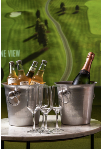 Wine, beer and glasses beside an indoor golf bay