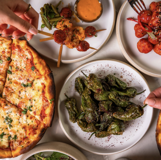 Sharing dishes including pizza and padron peppers